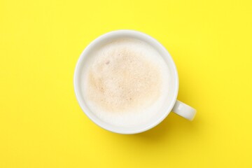 Aromatic coffee in cup on yellow background, top view