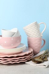 Beautiful ceramic dishware, cups and cutlery on light grey table