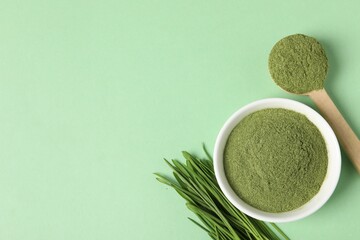 Wheat grass powder and fresh sprouts on green table, flat lay. Space for text