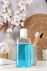 Bottle of mouthwash and toothbrushes on white table in bathroom
