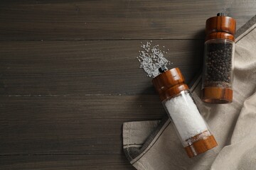 Salt and pepper shakers on wooden table, flat lay. Space for text
