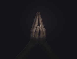 Christian woman praying in darkness, closeup. Belief