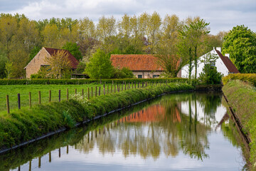 Traditional rural flemish architecture reflection with canal, Moere City, Bruges region, Flanders, Belgium.