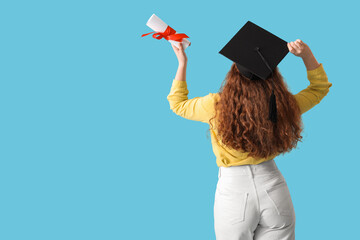 Female student in graduation hat with diploma on blue background, back view