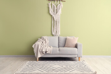 Interior of minimalist  living room with sofa, rug and decor near green wall