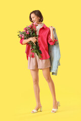 Young woman with pink roses on yellow background