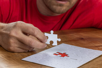 Blank puzzle with the missing piece being held next to the whole with a red placer where the last...