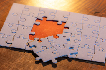 Blank puzzle with one missing piece next to the whole with a red placer where the last piece...