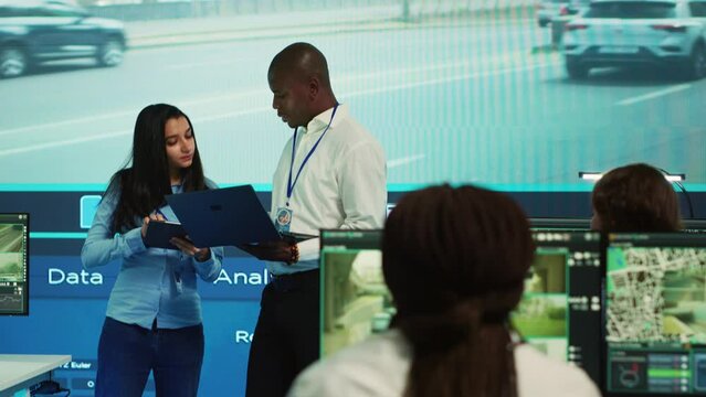 Team leaders reviewing traffic data collected from video surveillance footage, monitoring urban infrastructure by using CCTV cameras system. Government agency works on public safety. Camera A.