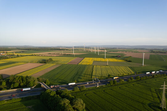 A road cutting through vibrant green grassland seen from above and wind turbines 5K drone view Hanover Wunstorf Kolenfeld Germany 