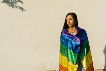 Hermosa joven hispanoamericana envuelta en una bandera del arco iris