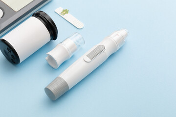 Glucometer on a blue background. Device for measuring blood sugar levels. Top view. Space for text.