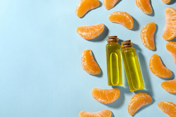 Aromatic tangerine essential oil in bottles and citrus fruits on light blue table, flat lay. Space...