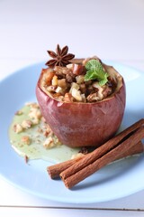 Tasty baked apple with nuts, honey, spices and mint on white wooden table, closeup