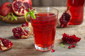 Tasty pomegranate juice in glass and fresh fruits on wooden table, closeup