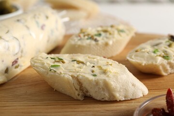 Tasty butter with olives, green onion and bread on wooden board, closeup