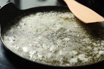 Melted butter in frying pan and wooden spatula on table, closeup