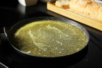 Melted butter in frying pan on cooktop, closeup