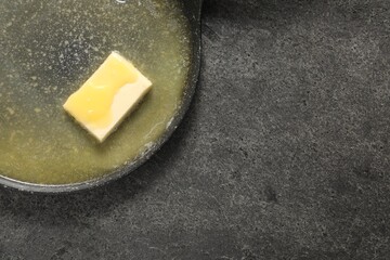 Melting butter in frying pan on grey table, top view. Space for text