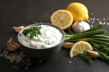 Delicious yogurt in bowl and ingredients on black table, closeup