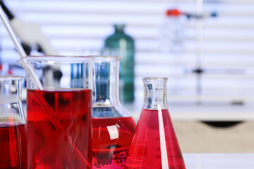 Laboratory analysis. Different glassware with red liquid on table indoors, closeup. Space for text