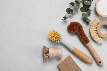 Cleaning brushes, baking soda, soap bar and eucalyptus on white table, flat lay. Space for text