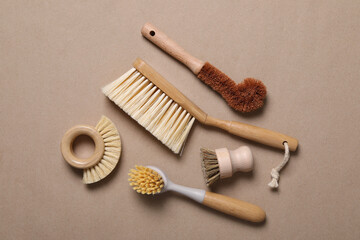 Cleaning brushes on pale brown background, flat lay