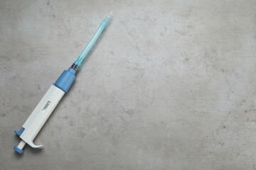 Laboratory analysis. Micropipette with liquid on grey table, top view. Space for text