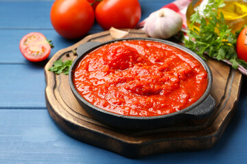 Homemade tomato sauce in bowl and ingredients on blue wooden table