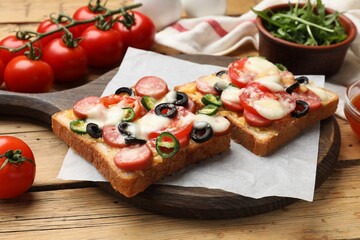 Tasty pizza toasts, arugula and tomatoes on wooden table
