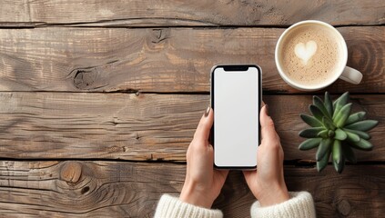 Woman's hands holding an iPhone with a white screen and wearing a sweater on a wooden table. - Powered by Adobe