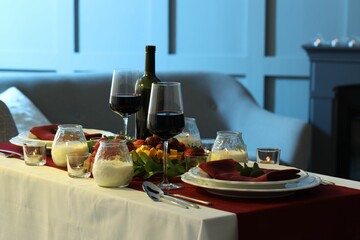 Stylish table setting with burning candles and wine indoors. Romantic dinner