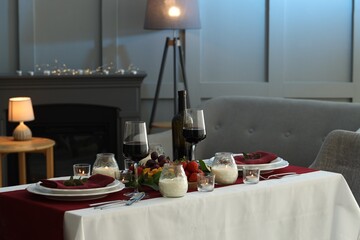Stylish table setting with burning candles and wine indoors. Romantic dinner