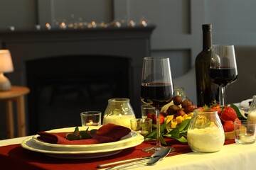 Stylish table setting with burning candles and wine indoors. Romantic dinner