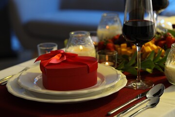 Stylish table setting with wine and gift box. Romantic dinner