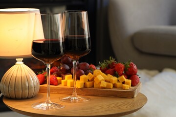 Glasses of wine and tasty snacks on wooden table. Romantic dinner