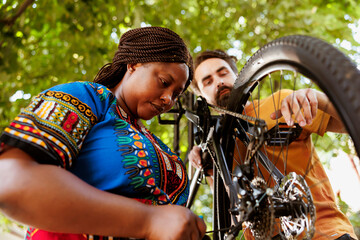 Sporty and eager black woman in yard repairing bike derailleur for summer recreational cycling....
