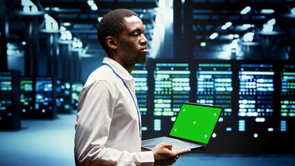 Engineer using green screen laptop to do maintenance on high bandwidth, dedicated game servers used...