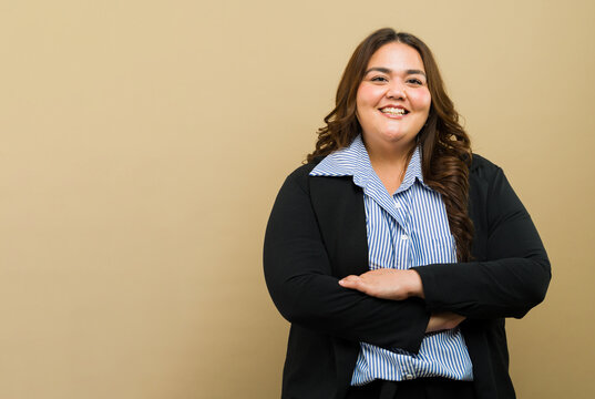 Smiling plus-size woman in professional attire stands confidently with arms crossed with some copy space - Powered by Adobe