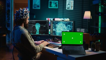 Engineer with EEG headset on programming brain transfer into computer virtual world next to green...