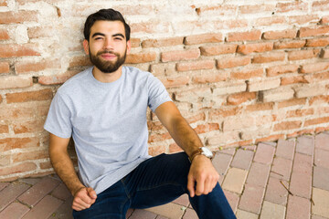 Handsome, young hispanic man smiling and posing in a blank grey t-shirt, ideal for mockup designs...