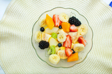 Imagen horizontal con un pato de frutas frescas a la derecha sobre un mantel blanco 