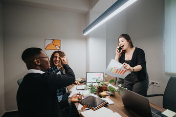 In a well-lit office, three diverse colleagues engage joyfully with business charts, one celebrating over a phone call, another sharing a high-five.