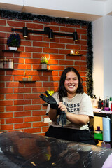 Young Latin female smiling tattoo artist getting ready for a tattoo session with her client. Safety...