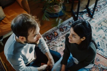 Obraz premium A man and a woman are sitting on the floor, talking to each other