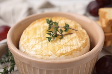 Tasty baked camembert in bowl on table, closeup