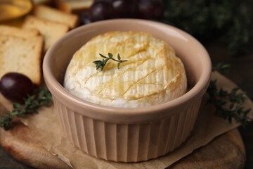 Tasty baked camembert in bowl on table, closeup