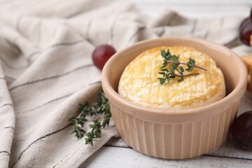 Tasty baked camembert and thyme in bowl on table, closeup