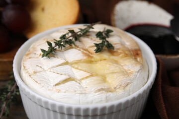 Tasty baked camembert and thyme in bowl on table, closeup