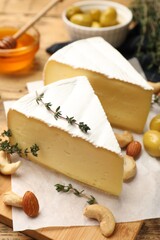 Tasty Camembert cheese with thyme, honey and nuts on wooden table